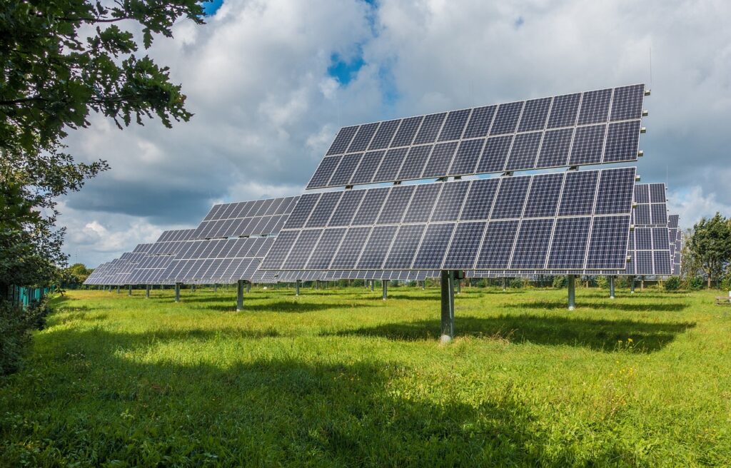 Placas solares dispostas em um gramado verde, capturando a energia solar para produção de energia limpa e renovável